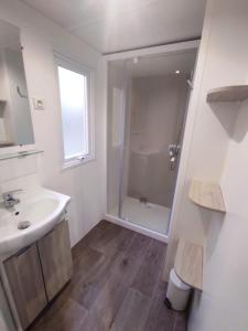 uma casa de banho branca com um chuveiro e um lavatório. em Family's Camping Le Savoy em Challes-les-Eaux