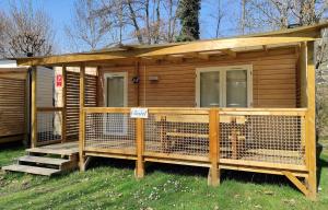 eine Holzhütte mit einem Hund in einem Käfig in der Unterkunft Family's Camping Le Savoy in Challes-les-Eaux