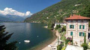 un cuerpo de agua con un edificio y un barco en él en Villa Marina - Como lake, en Bellano