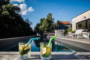 two drinks sitting on a table next to a swimming pool at Au Calme de Hosdent in Braives