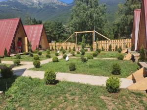 a garden with trees and bushes in front of buildings at PROKLETIJE COTTAGES in Plav +47 photos