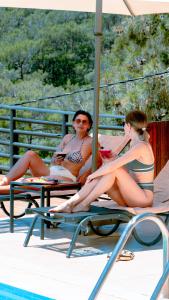 two people sitting on chairs next to a swimming pool at Tree Houses Hotel in Fethiye