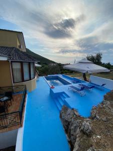 a blue pool with an umbrella next to a house at Villa Loridis in Prinos