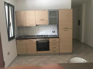 a kitchen with wooden cabinets and a stove top oven at Casa Camere Pistis in Assemini