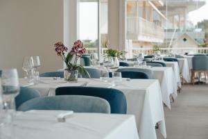 a row of white tables with blue chairs and flowers at Hotel Galassia Suites & Spa in Lido di Jesolo