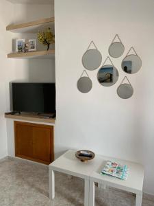 sala de estar blanca con mesa y TV en La Casita de Mari, en Estepona