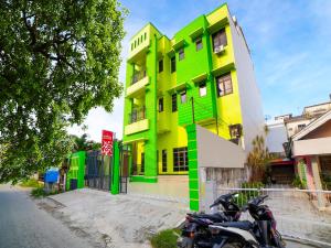 a green and yellow building with motorcycles parked in front at OYO 91283 Sg Premium Guest House in Medan