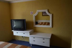 1 dormitorio con TV y tocador con espejo en Hotel San Jeronimo Inn, en Toluca