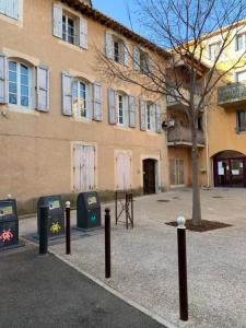 a building with a tree in front of a building at Studio cosy dans le centre-ville historique in LʼIsle-sur-la-Sorgue