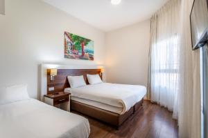 Habitación de hotel con 2 camas y ventana en Aviv Holiday Flat, en Tiberíades