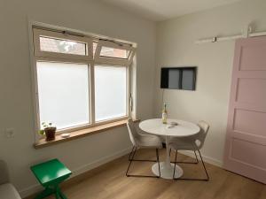 einen weißen Tisch und Stühle in einem Zimmer mit Fenster in der Unterkunft ‘t Hoekje 49 in Biggekerke