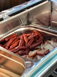 a pan full of sausage and potatoes in a buffet at Hotel Sweet in Mamaia Nord