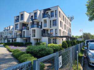 a white apartment building with cars parked in front of it at Modernūs apartamentai Šventojoje 100m iki jūros in Palanga