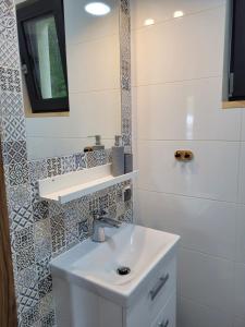 a white bathroom with a sink and a mirror at DĘBKI DOMKI SASANKOWE in Dębki +32 photos