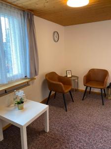 a room with two chairs and a table and a clock at Simple Room 1 in Oberbüren