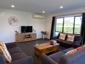 a living room with couches and a flat screen tv at Unique Equestrian Lifestyle in Tamahere