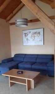 ein blaues Sofa im Wohnzimmer mit einem Tisch in der Unterkunft Apartmani i restoran Stara Pošta in Novi Vinodolski