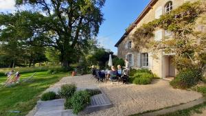 a group of people sitting at a table in front of a house at Domaine des Roches Blanches in Le Pin