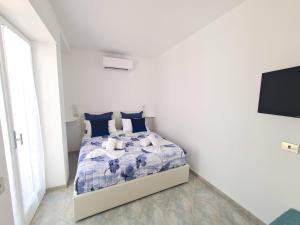 a white bedroom with a bed with a blue comforter at Tiberio House & Spa in Capri