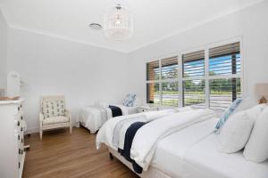 a white bedroom with two beds and a window at Arborea Country Holiday House catering for 14 to 16 guests In the heart of Bowral in Bowral