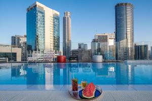 a pool with a tray of watermelon slices on a plate at Hotel Indigo Tel Aviv - Diamond District, an IHG Hotel in Tel Aviv