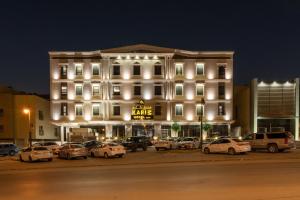 ein großes weißes Gebäude mit Autos auf einem Parkplatz in der Unterkunft Karim Hotel Riyadh in Riad