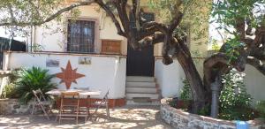 a table and chairs in front of a house with a tree at Villa dei Focesi in Ascea