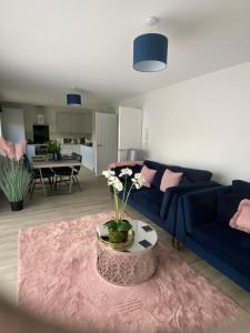 uma sala de estar com um sofá azul e uma mesa com flores em The Bay house Apartments , shanklin em Shanklin