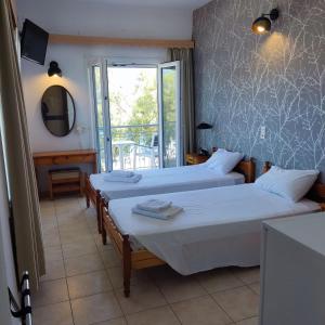um quarto com duas camas e um espelho e uma janela em Hotel Ilion em Pétra