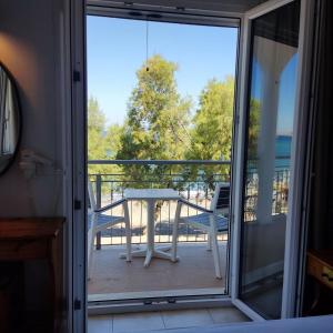 una porta scorrevole in vetro che conduce a un balcone con tavolo di Hotel Ilion a Pétra
