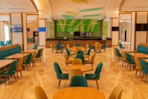 塞拉莱Tulip Inn Majan Hotel and Suites Salalah的一间设有桌椅和大屏幕的自助餐厅