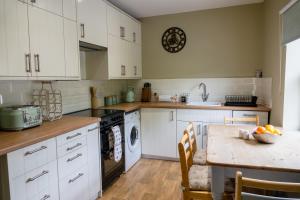 a kitchen with white cabinets and a wooden table at Acorn Apartment in York