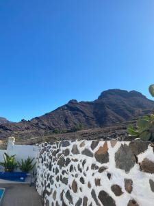 a stone wall with mountains in the background at Casa en Mogán in Las Burrillas