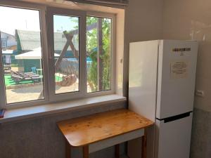 uma cozinha com um frigorífico e uma mesa ao lado de uma janela em Guest House Apelsin em Yeysk