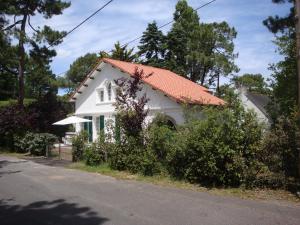 uma pequena casa branca com um telhado laranja em Maison basque dans les pins, au calme, 200m plage em La Baule