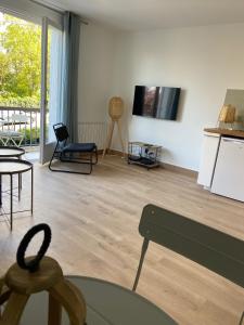 a living room with a table and a tv on the wall at JADE, STUDIO au coeur de la ville in Villers-sur-Mer