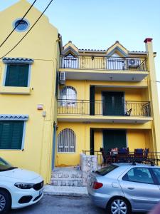 two cars parked in front of a yellow building at Chloe attic in Agia Effimia