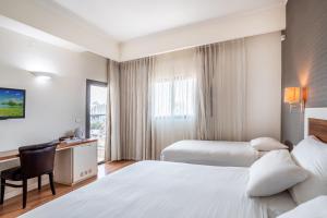 um quarto de hotel com duas camas e uma secretária em Emily's Hotel em Tiberias
