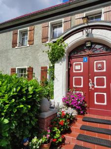 a red front door of a house with flowers at Agroturystyka u Strażaka in Świeradów-Zdrój