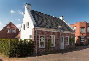 a white and red house with a black roof at Karakteristiek huis in centrum Winsum met nieuwe badkamer in Winsum