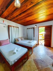 two beds in a room with wooden ceilings at Pousada Dunas do Icarai in Icaraí