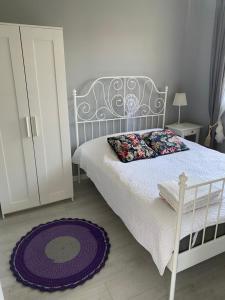 a bedroom with a white bed and a purple rug at Rodzinne miejsce in Kopalino