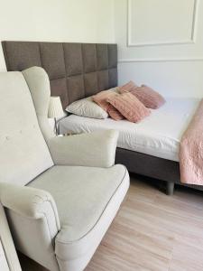 a bed and a chair in a room at Pokoje Gościnne i Apartamenty Ula in Ustronie Morskie