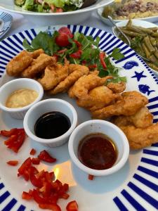 a plate of food with onion rings and dipping sauces at Yilmaz Hotel in Ortakent