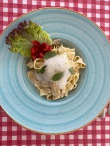 un plato azul con pasta y brócoli en una mesa en Yilmaz Hotel, en Ortakent