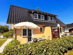 a yellow house with a table and an umbrella at Ferienhaus Anna - rechte Seite in Dranske