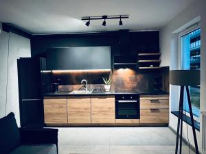 a kitchen with black cabinets and a sink at Apartament Husarska in Rumia