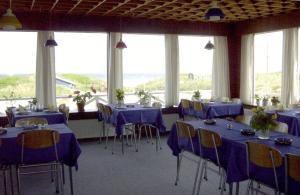 a room with blue tables and chairs and windows at Munchs Badehotel in Hirtshals