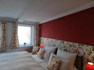 a bedroom with a bed and a red wall at Ferienwohnung Teestube Wernigerode "Rose" in Wernigerode