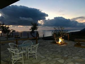 a patio with a table and chairs next to a fire at Rahoni Park & Suites in Dhërmi